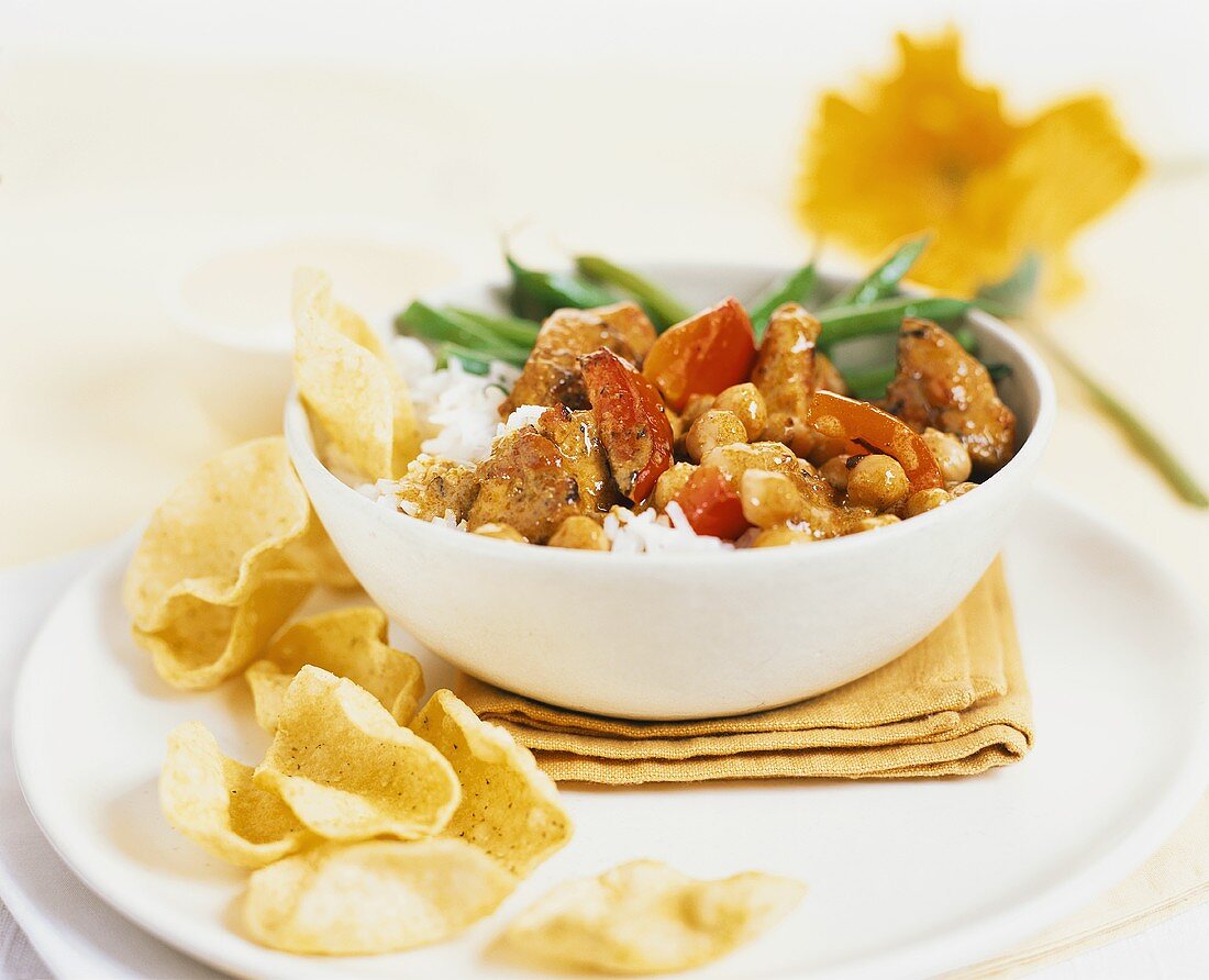 Schweinefleisch mit Paprika, Kichererbsen, Reis und Chips