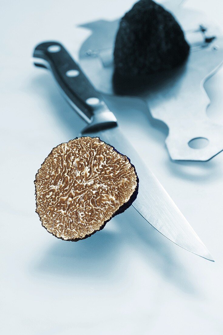 Black truffle, sliced through, knife and truffle slicer