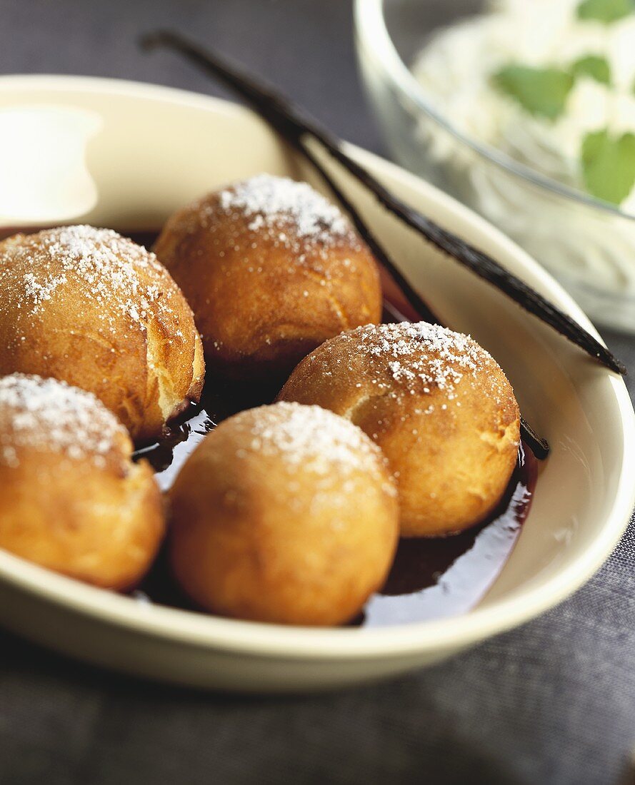 Gebackene Teigbällchen mit Puderzucker in Rotweinsauce