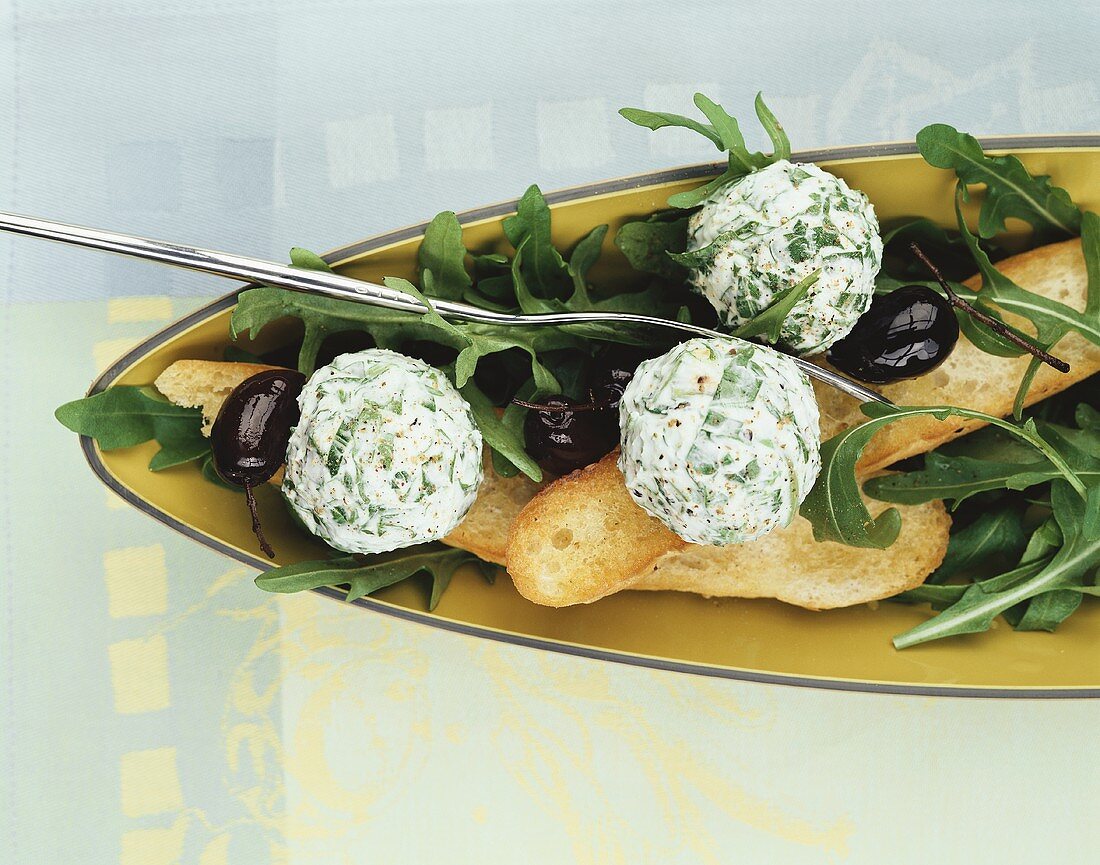 Fresh cheese balls with rocket, with olives and white bread