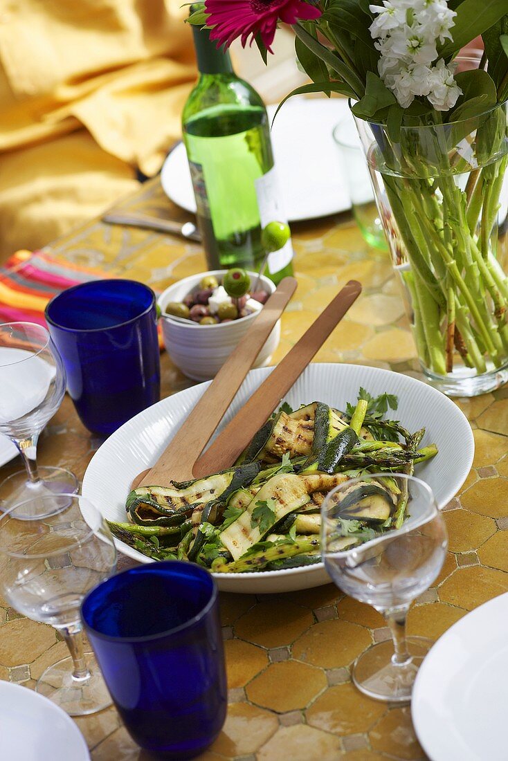 barbecued courgette strips with herbs on table in open air