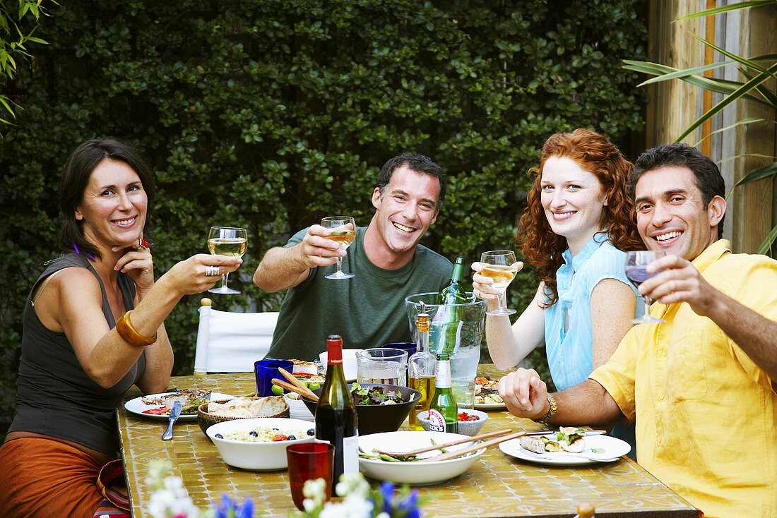 People raising wine glasses at party in garden