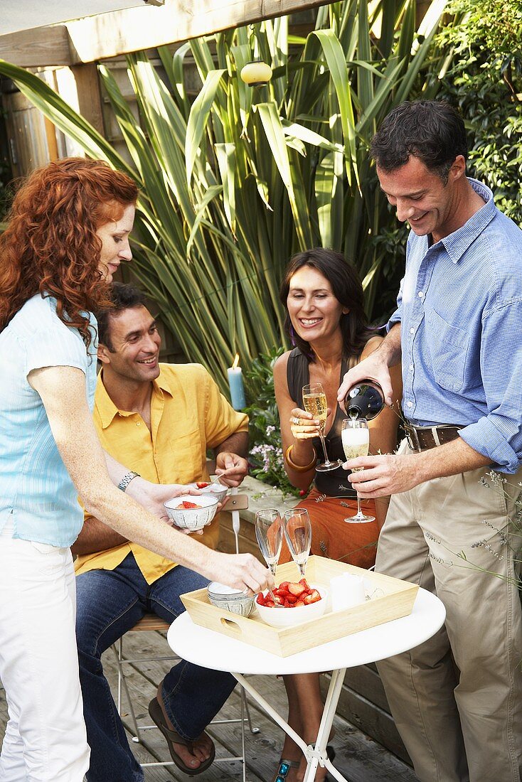 Man serving Sekt to drink with  dessert at garden party