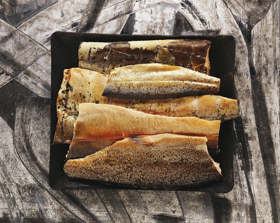 An assortment of smoked fish on black platter