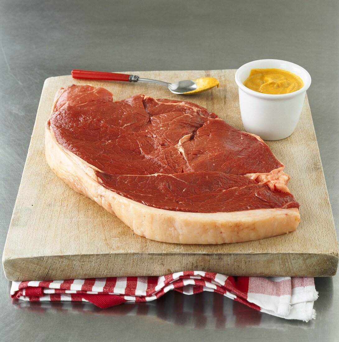 Beef steak with mustard on chopping board