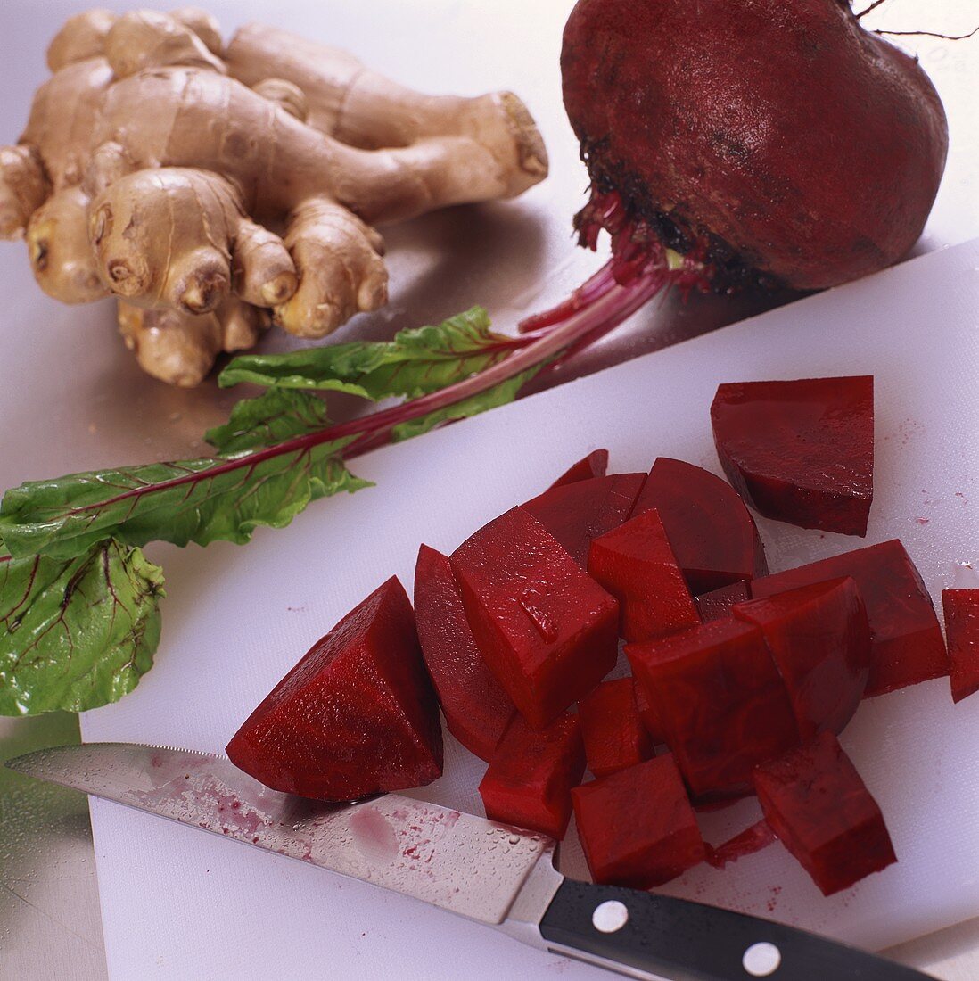 Diced beetroot on chopping board with knife, ginger