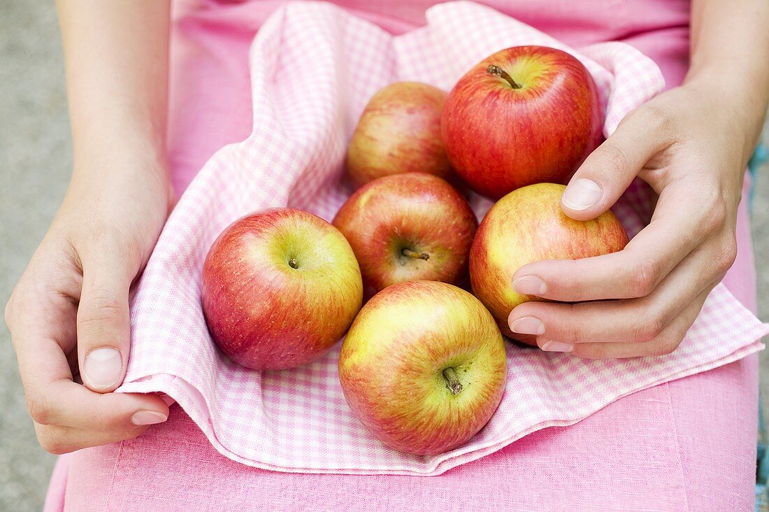 Sitzende Frau hält frische Äpfel auf kariertem Tuch