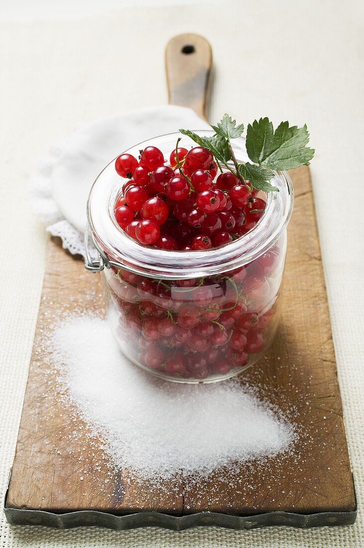 Redcurrants in jam jar, sugar beside it