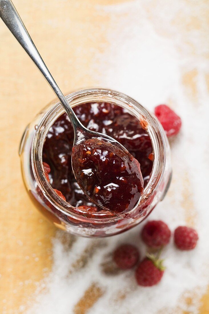 Jar of raspberry jam, sugar and fresh raspberries