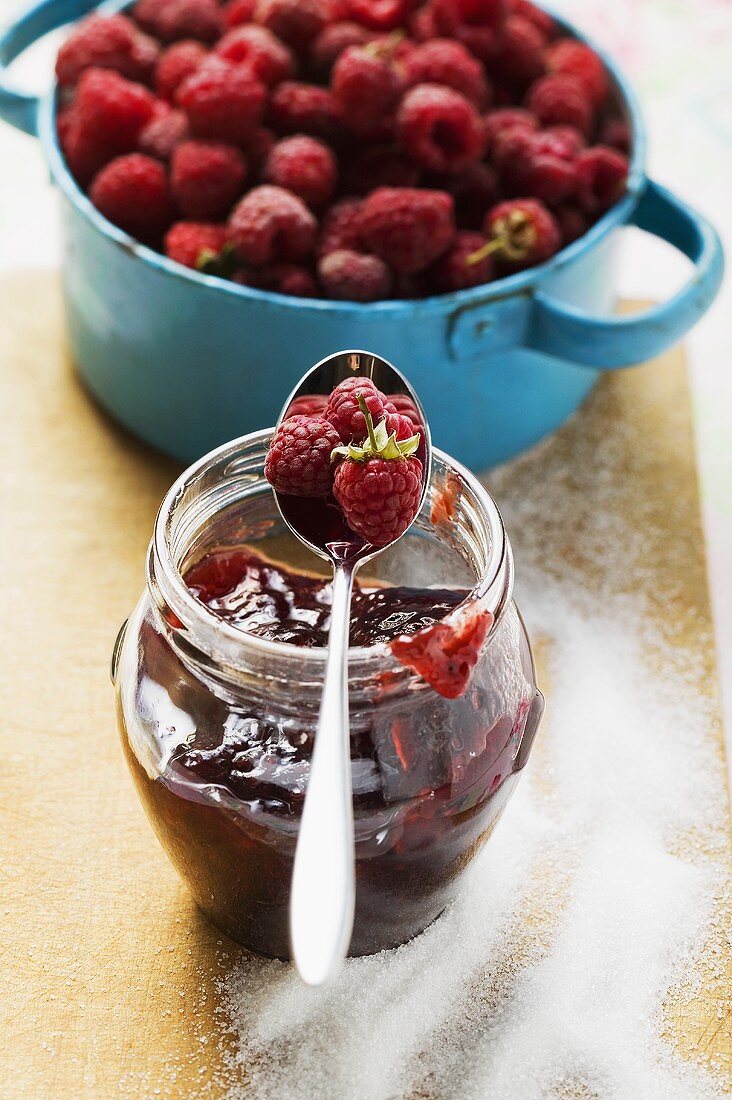 Glas Himbeermarmelade, Zucker und frische Himbeeren