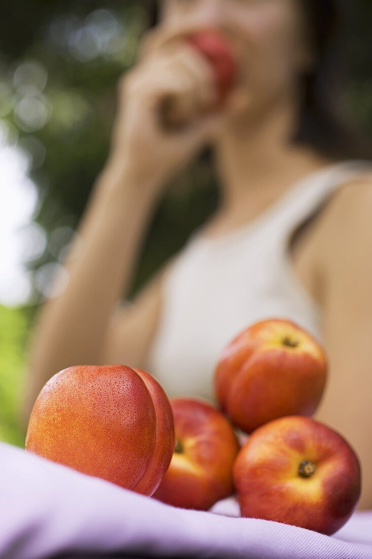 A few nectarines in front of woman eating nectarines