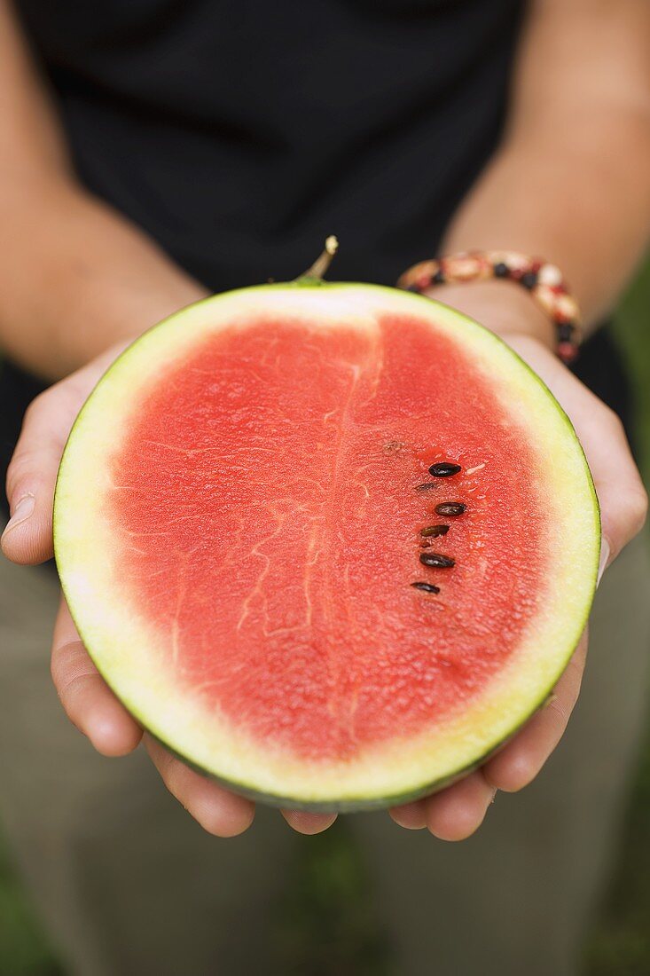 Hands holding half a watermelon
