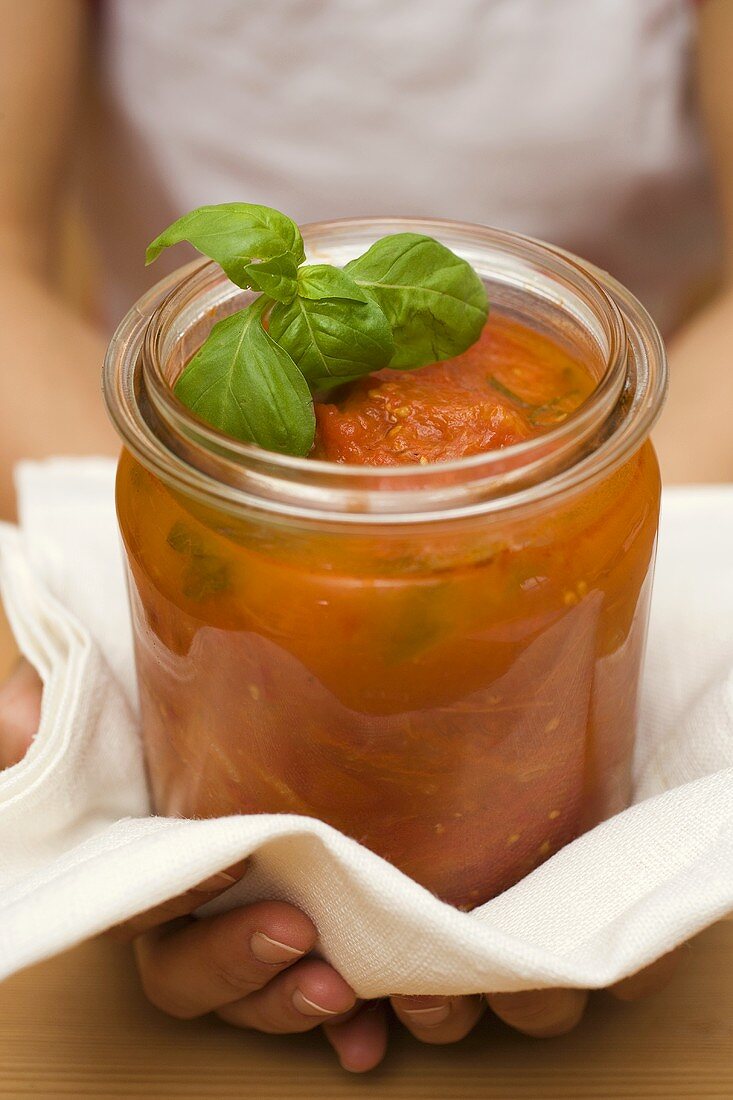 Hände halten Glas mit selbstgemachter Tomatensauce