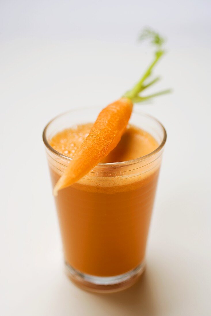 Glass of carrot juice and fresh peeled carrot
