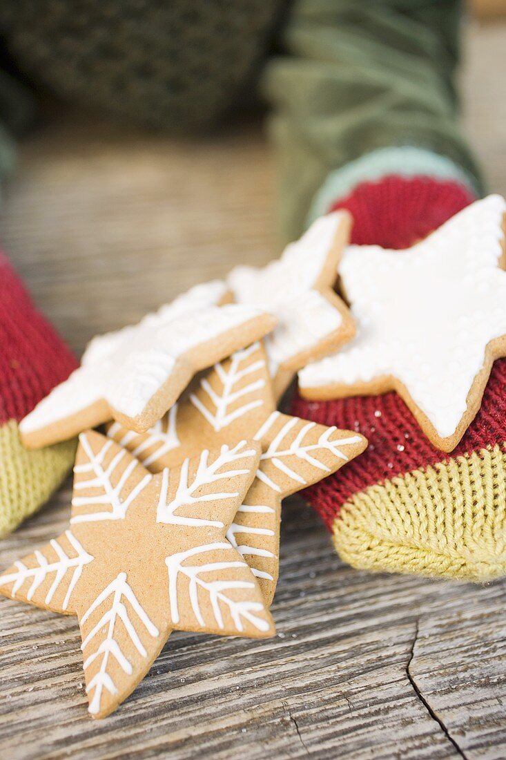 Hands in woollen mittens holding gingerbread stars