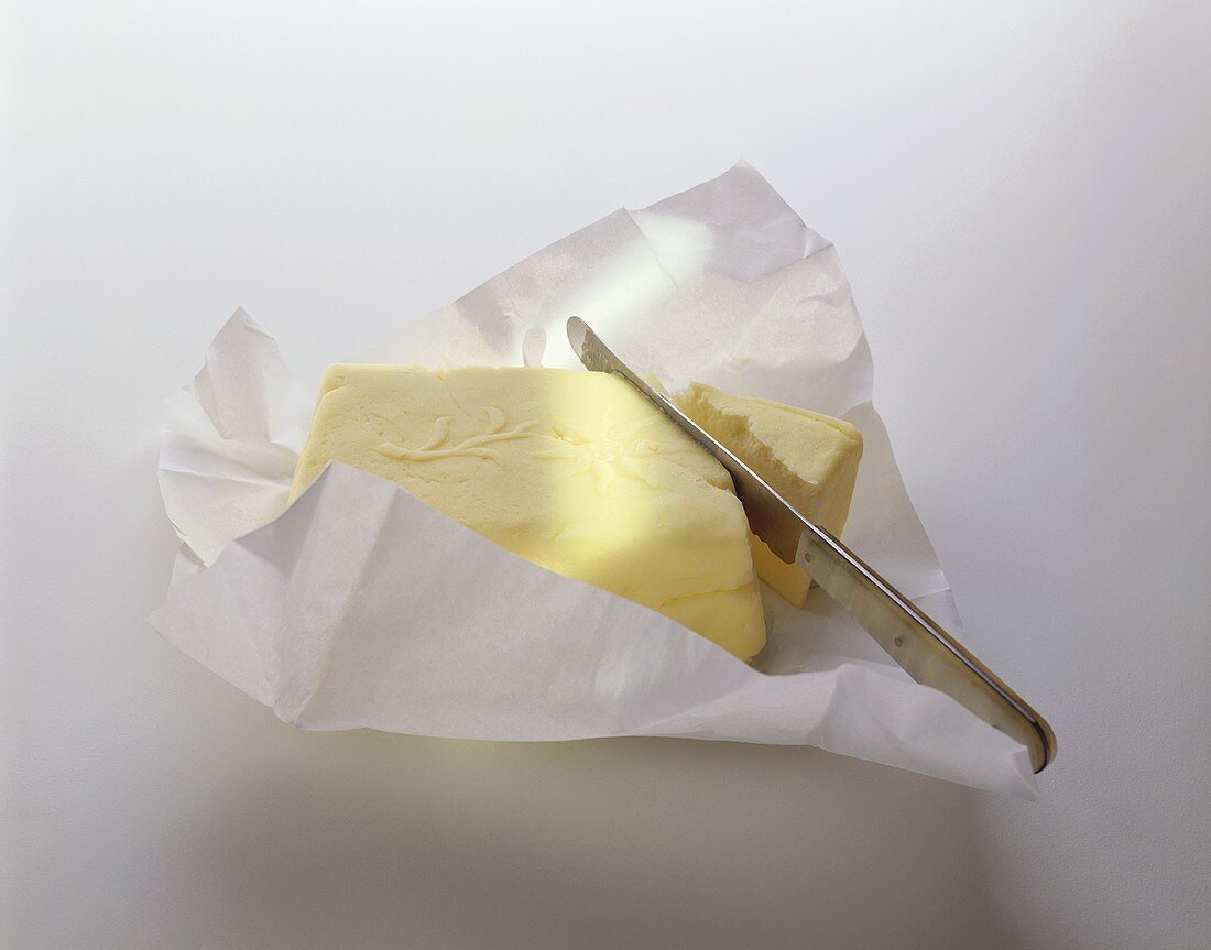 Butter im Einwickelpapier mit Messer