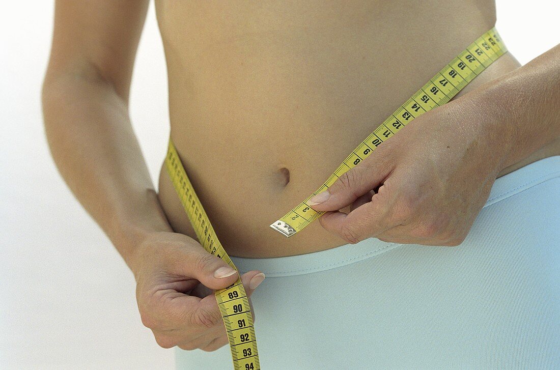 Person measuring their waist with tape measure