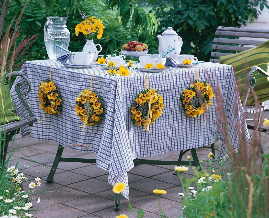 Gedeckter Tisch im Freien mit sommerlichen Blumenkränzen