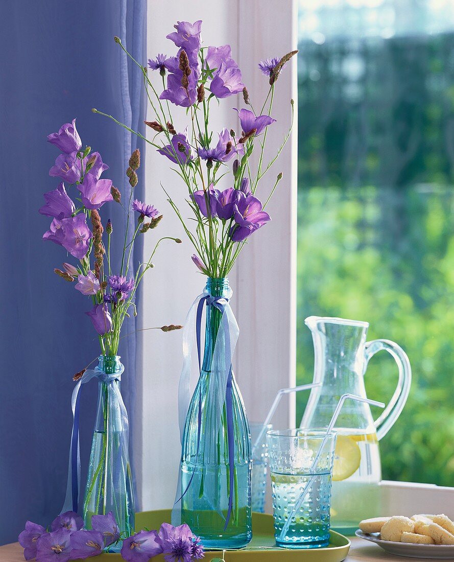 Campanulas, cornflowers and grasses in blue bottles