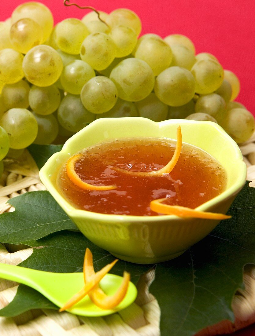 Grape jelly in bowl in front of fresh green grapes