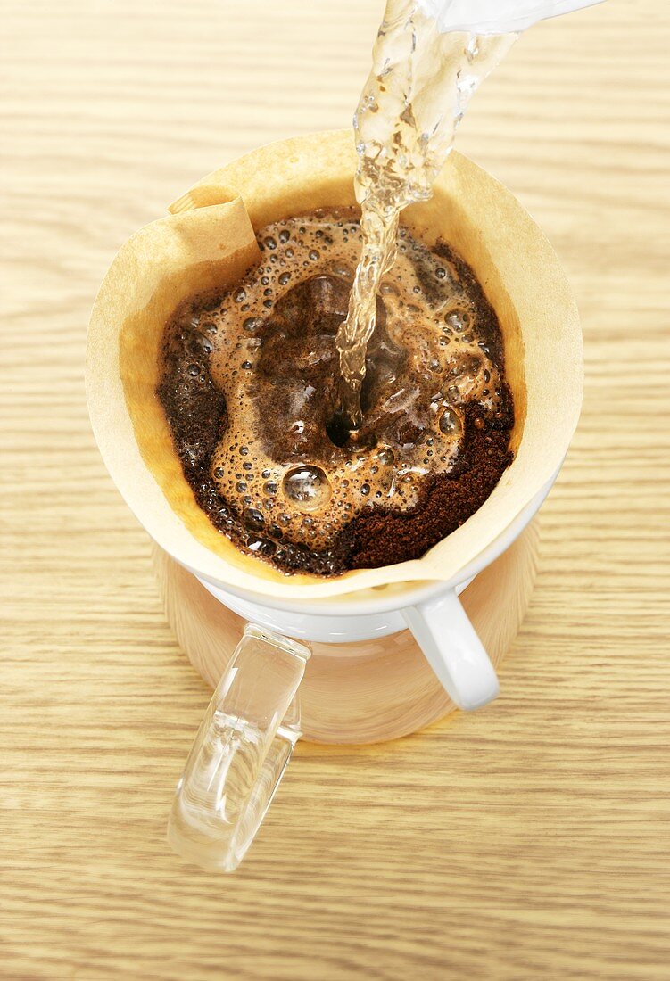 Heisses Wasser auf Kaffeepulver im Kaffeefilter gießen