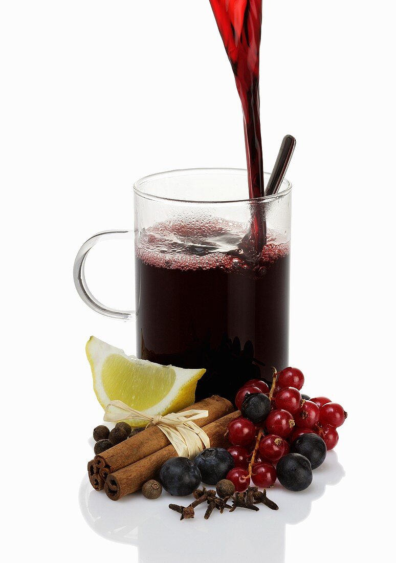Pouring mulled wine into glass, ingredients in foreground