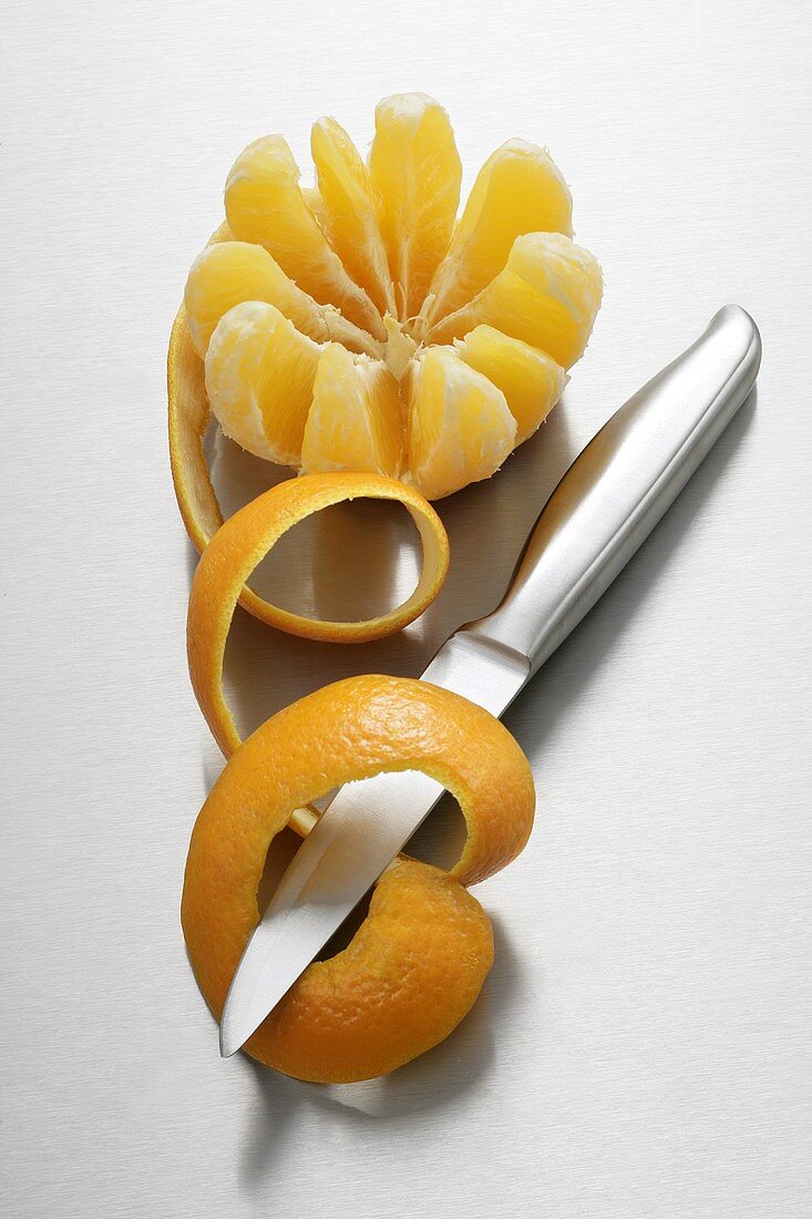 Orangenschale, Messer und aufgeschnittene Orange
