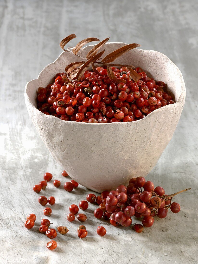 Red peppercorns in and beside bowl