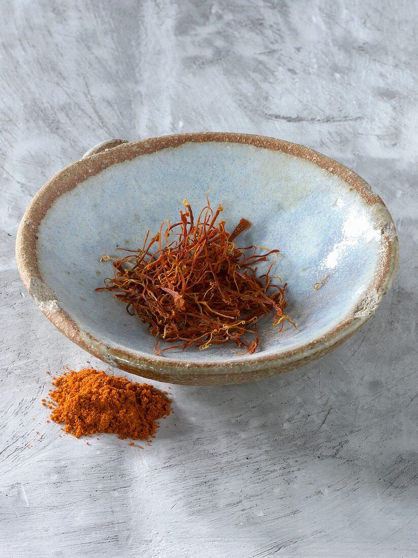 Saffron threads in bowl, saffron powder beside it