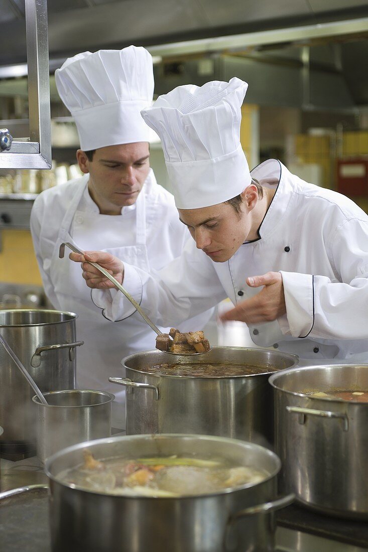 Chefs examining the contents of a pan