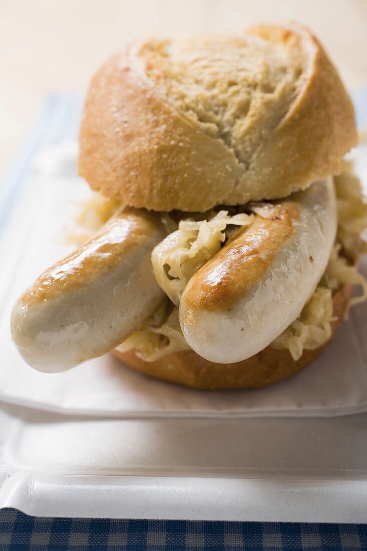 Brötchen mit Grillwurst und Sauerkraut auf Pappteller