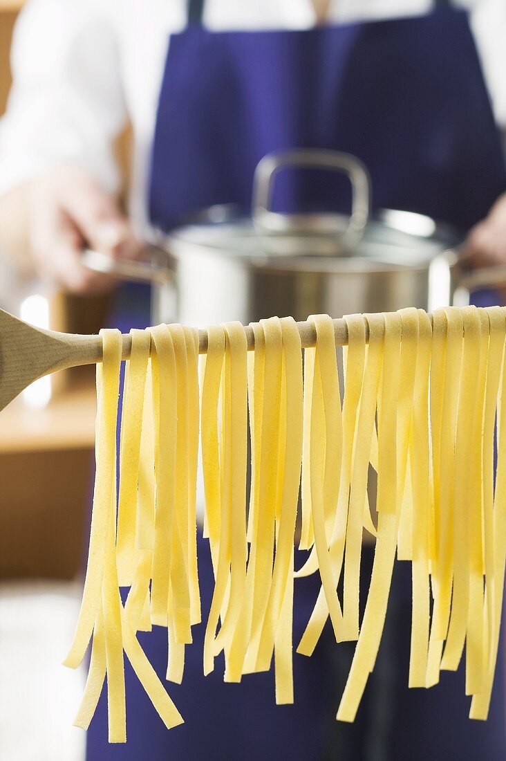 Home-made ribbon pasta on wooden spoon