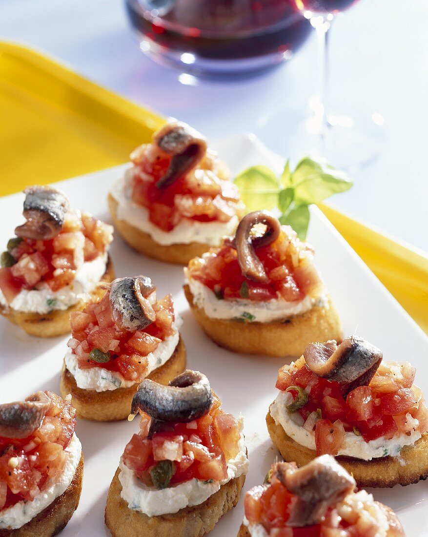Crostini with tomatoes, soft cheese and anchovy fillets