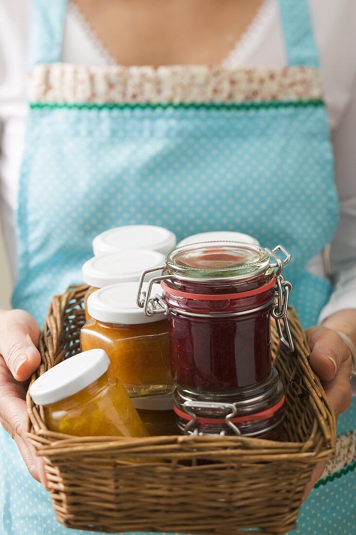 Woman holding a basket full of jars of jam