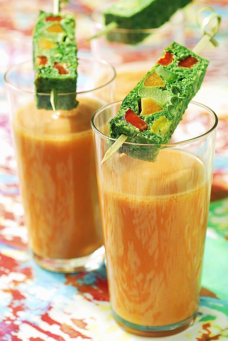Two glasses of gazpacho, vegetable terrine on cocktail sticks