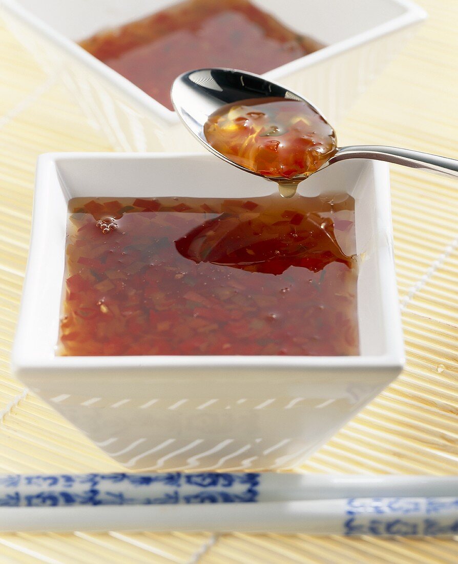 Spicy chilli sauce in bowl and on spoon