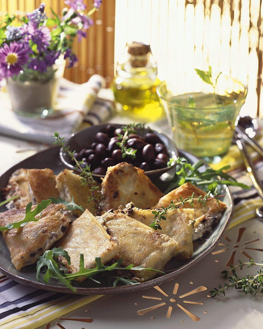 Slices of fried goat's cheese with olives and herbs