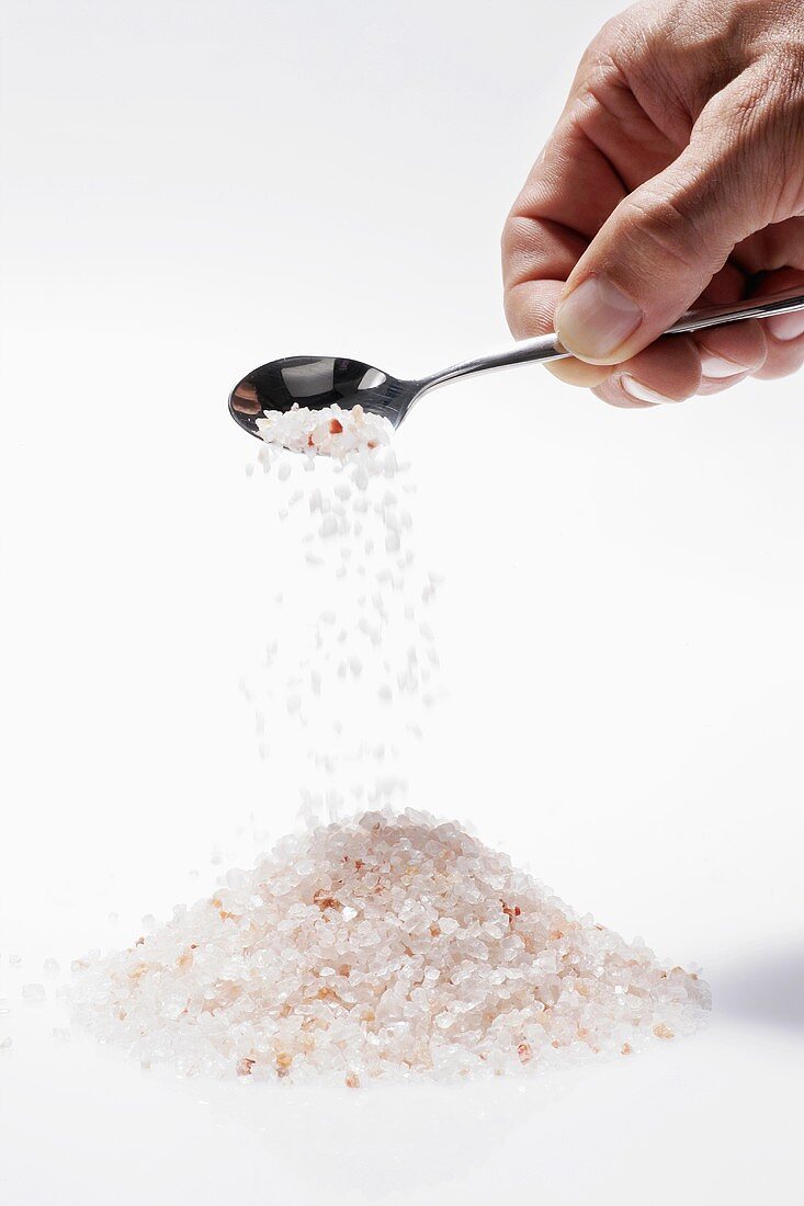 Sprinkling Himalayan salt onto heap from spoon