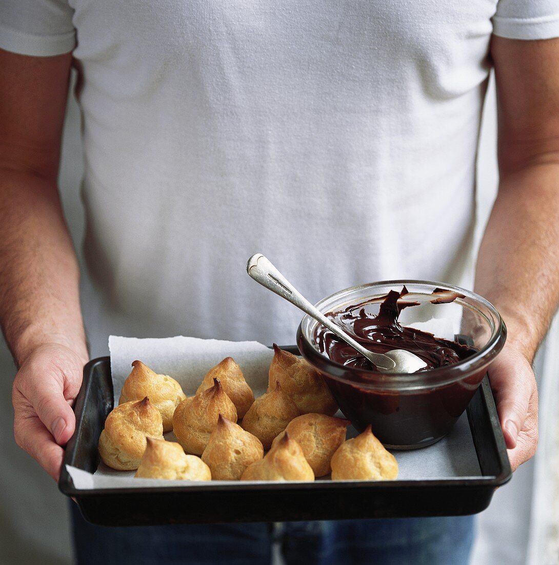Man serving profiteroles with chocolate sauce