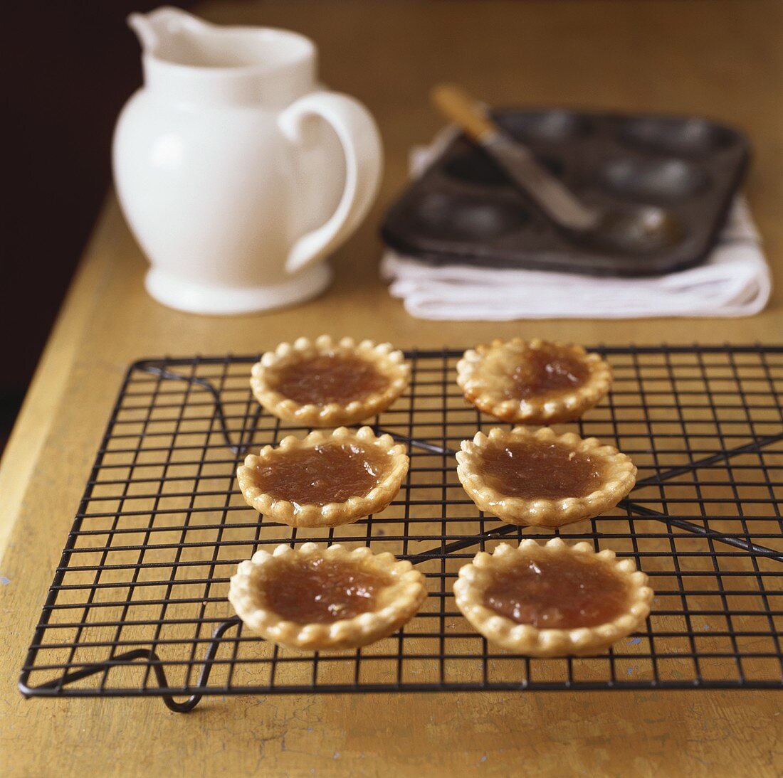 Six jam tarts on cake rack