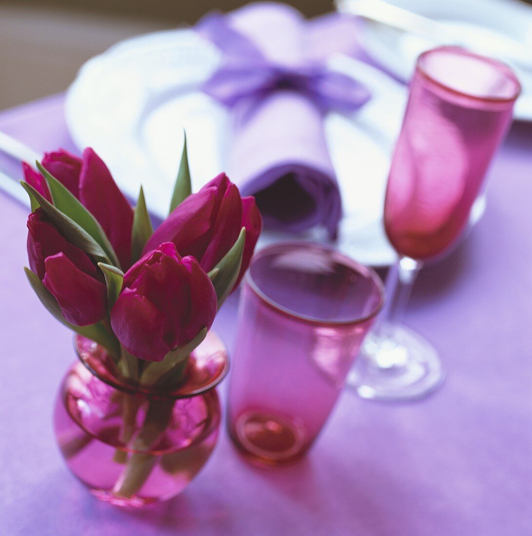 Rote Tulpen in kleiner Vase neben Gedeck