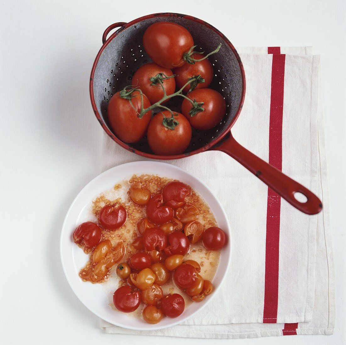 Cooked cherry tomatoes on plate, fresh tomatoes in strainer