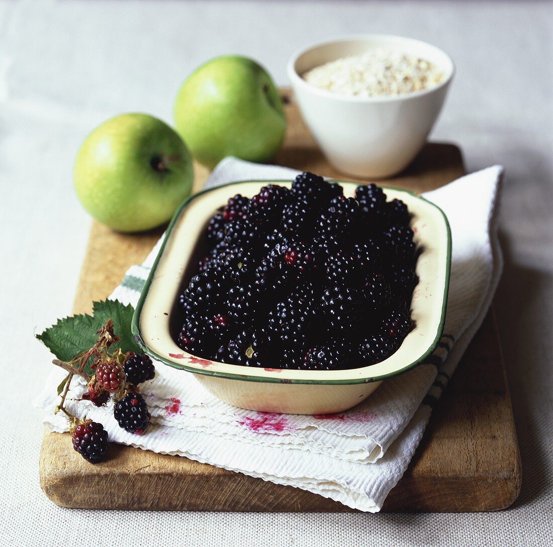 Blackberries in a dish, two green apples & rolled oats