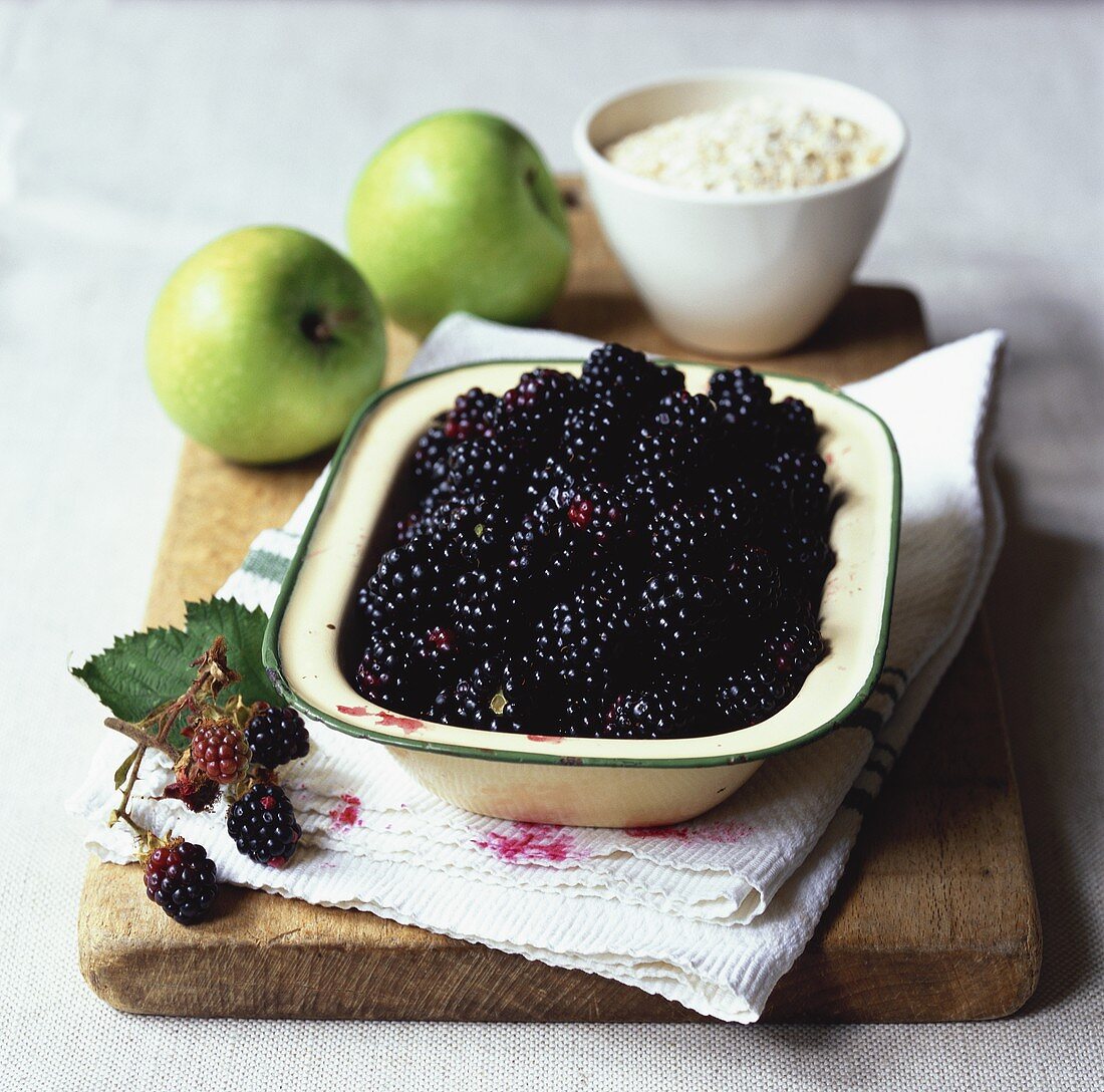 Brombeeren in Schüssel, zwei grüne Äpfel und Haferflocken