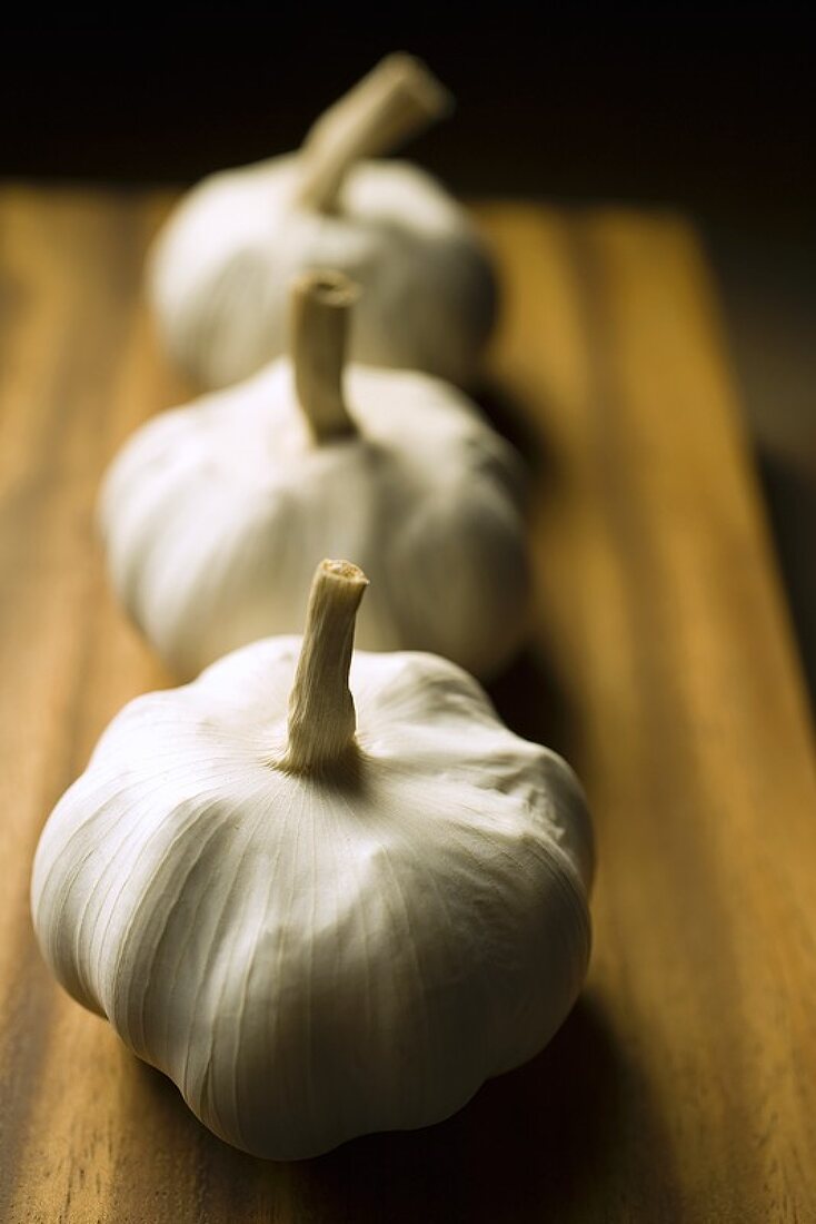 Three garlic bulbs on a chopping board