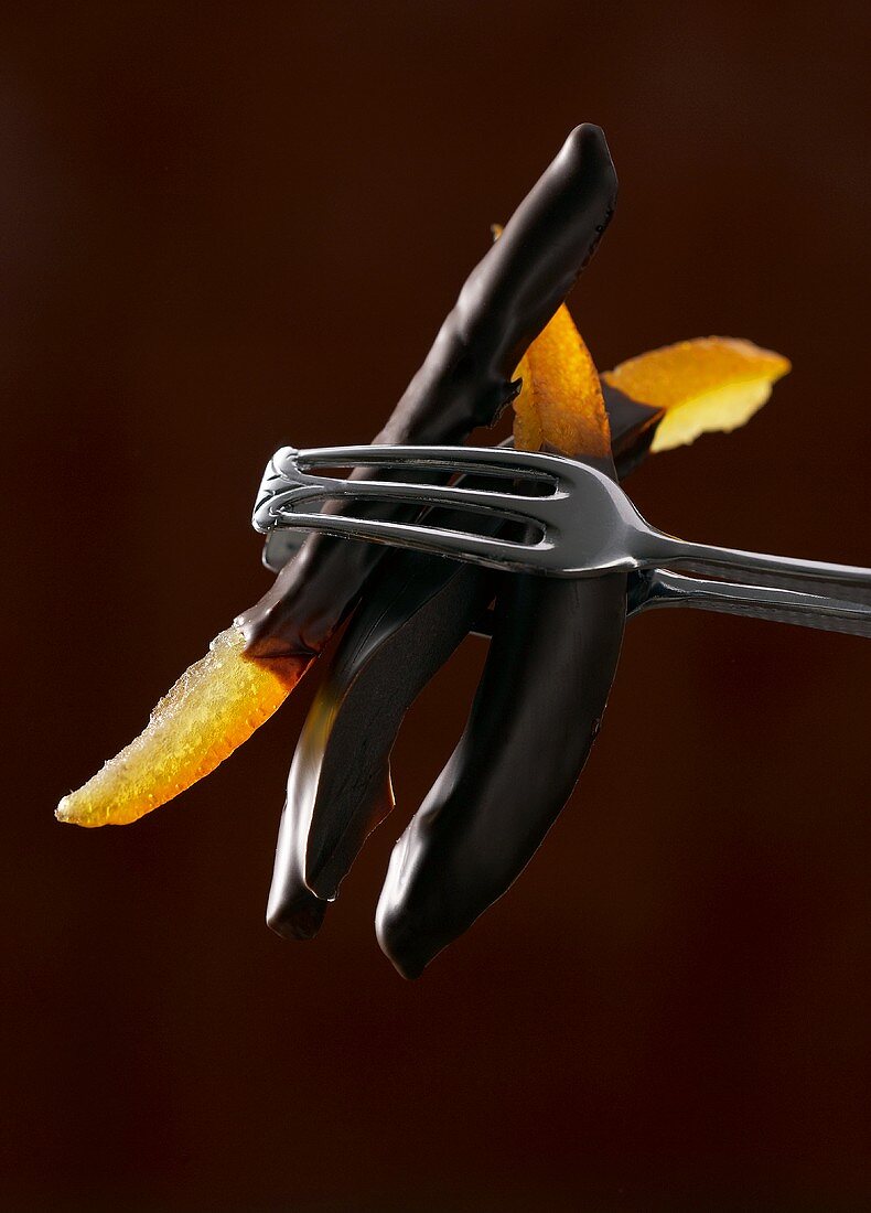 Zange hält kandierte Orangen mit Schokoglasur