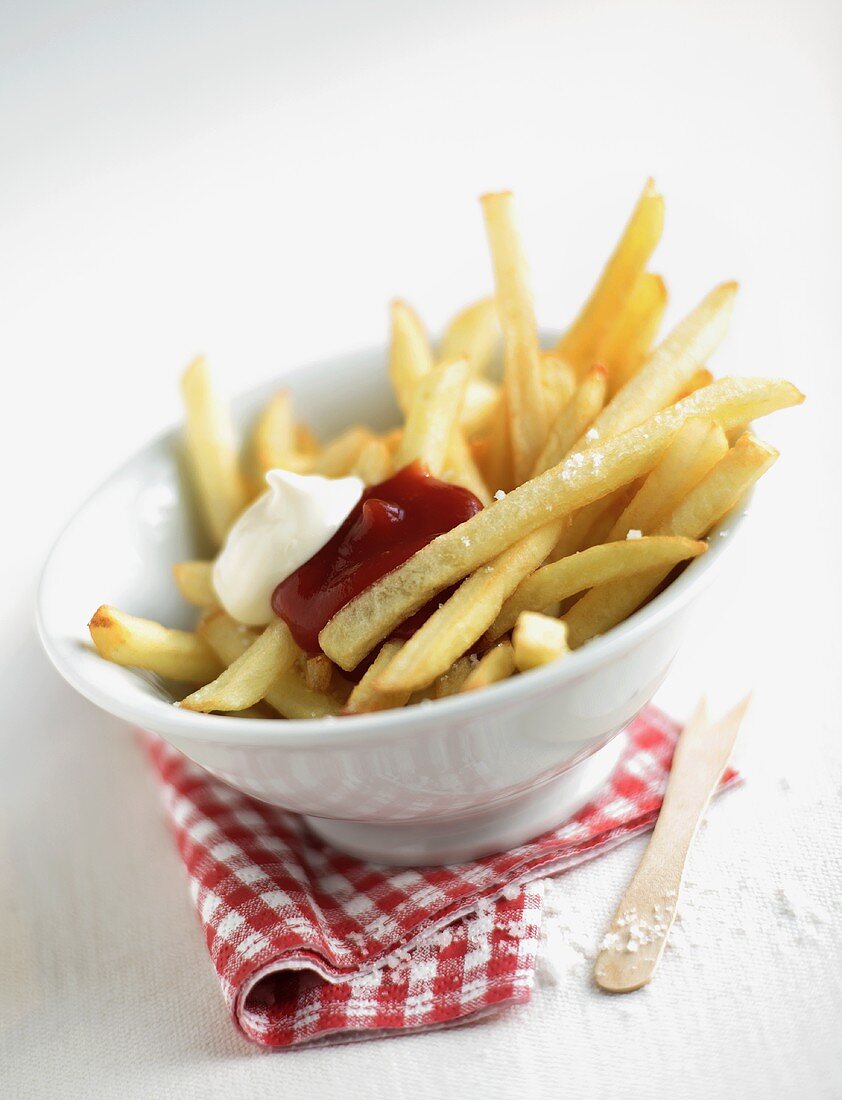 Chips with salt, ketchup, mayonnaise in white dish