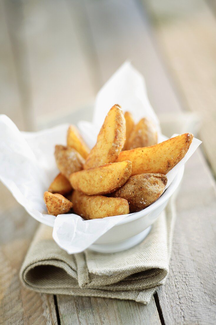 Potato wedges on paper napkin in dish