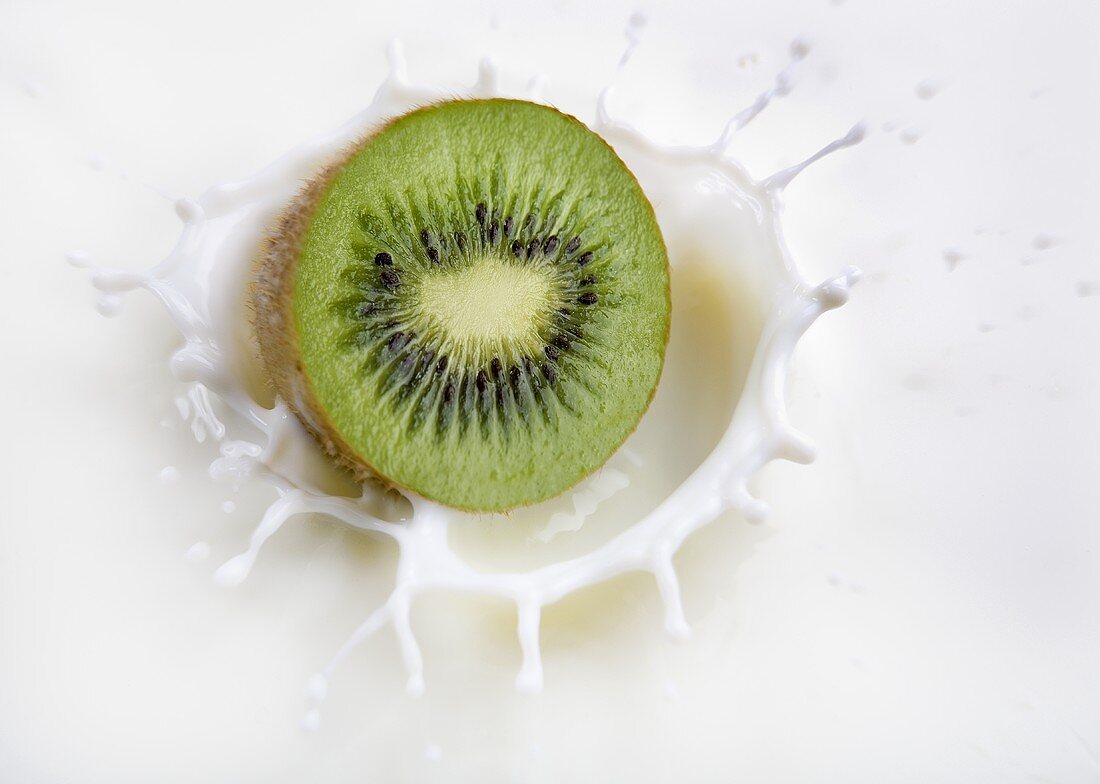 Kiwi fruit falling into milk