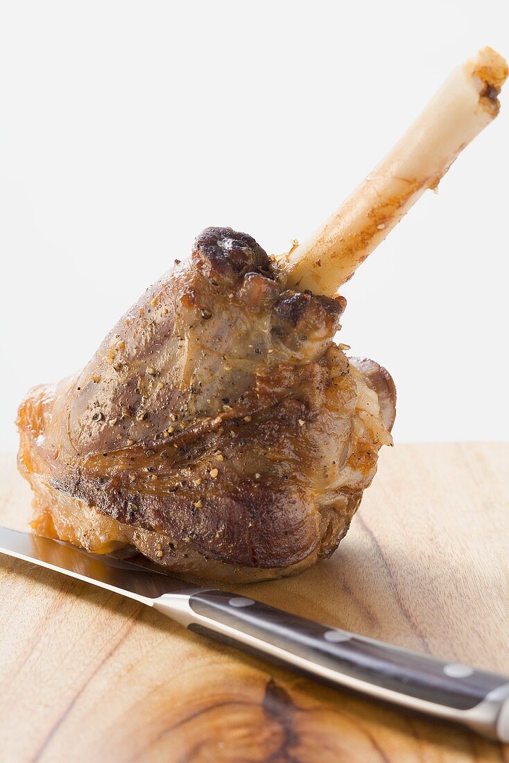 Roast leg of lamb on chopping board with knife